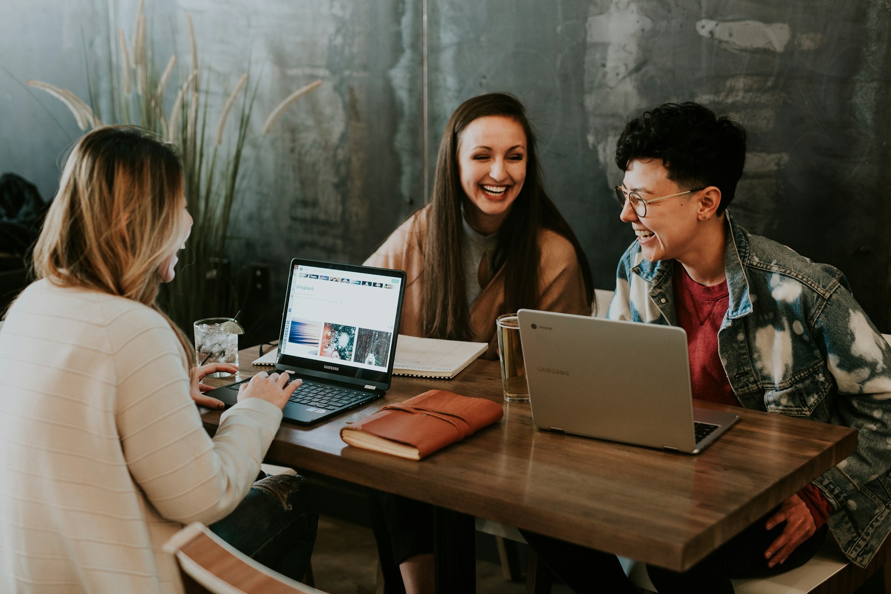 Three colleagues sharing ideas and laughing together around a table